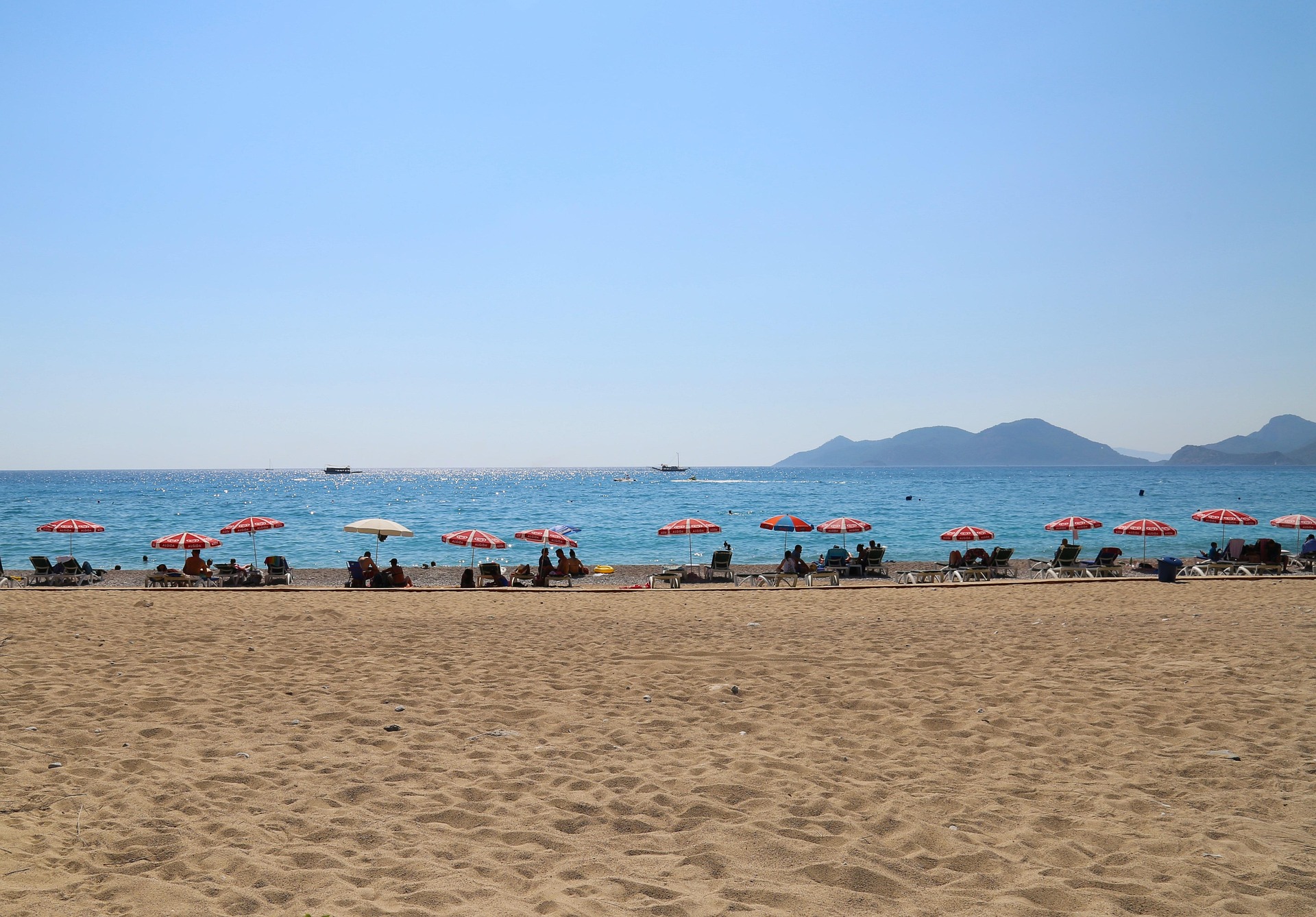 Güzel plaj ve deniz manzarası, şemsiye ve şezlonglarla rahatlama alanı, tatil ve dinlenme için ideal.